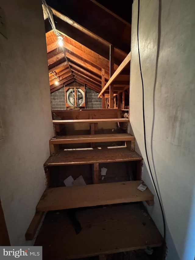 staircase featuring brick wall and vaulted ceiling