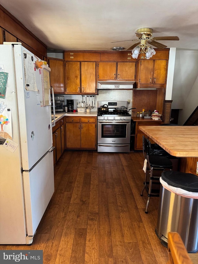 kitchen featuring backsplash, gas range, dark hardwood / wood-style floors, ceiling fan, and white fridge