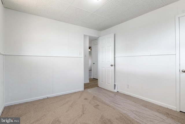 empty room with a paneled ceiling and light carpet