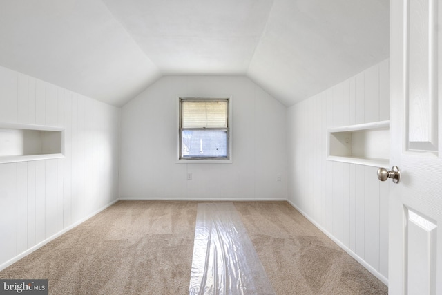 additional living space featuring vaulted ceiling and light colored carpet