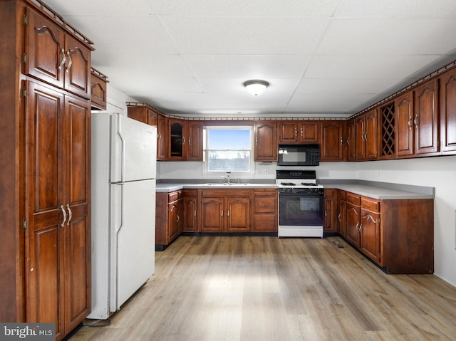 kitchen with sink, white appliances, a paneled ceiling, and light hardwood / wood-style floors