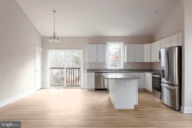 kitchen featuring stone counters, a kitchen island, decorative light fixtures, white cabinets, and appliances with stainless steel finishes