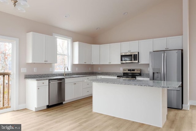 kitchen featuring a center island, stainless steel appliances, white cabinetry, and light stone counters