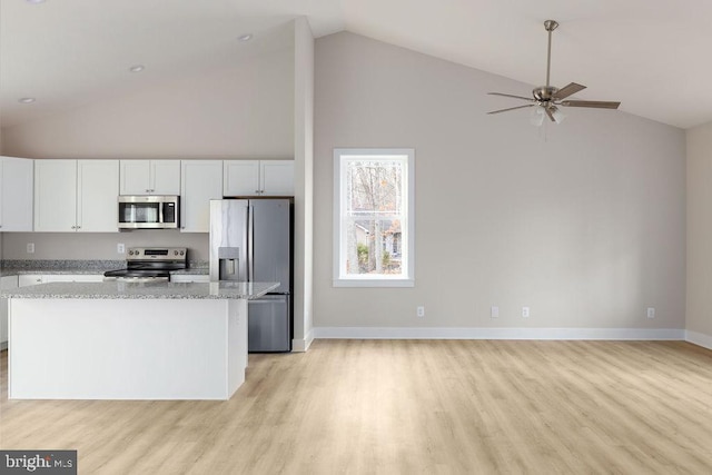 kitchen featuring appliances with stainless steel finishes, light stone counters, a kitchen island, ceiling fan, and white cabinetry