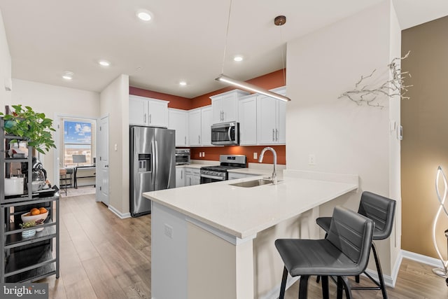 kitchen with pendant lighting, white cabinets, sink, kitchen peninsula, and stainless steel appliances