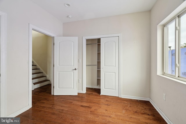 unfurnished bedroom with multiple windows, dark hardwood / wood-style floors, and a closet