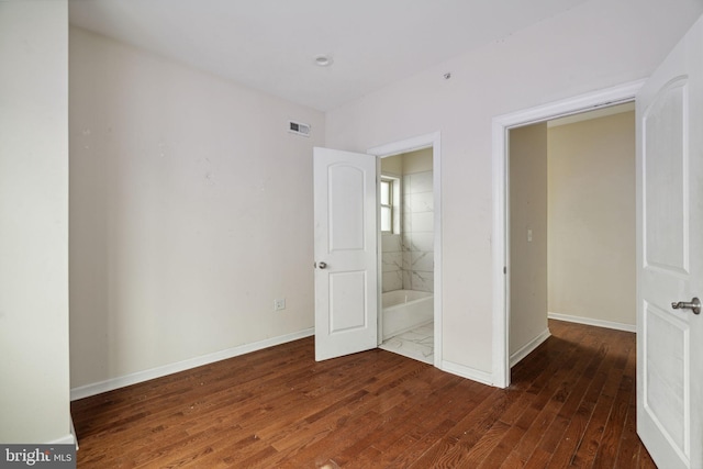 unfurnished bedroom featuring connected bathroom and dark hardwood / wood-style flooring