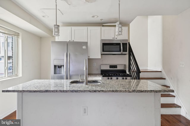 kitchen featuring light stone counters, stainless steel appliances, a kitchen island with sink, pendant lighting, and white cabinets