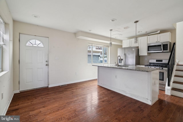 kitchen with white cabinetry, stainless steel appliances, dark hardwood / wood-style flooring, pendant lighting, and a center island with sink