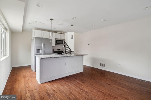 kitchen with appliances with stainless steel finishes, dark hardwood / wood-style flooring, sink, white cabinets, and hanging light fixtures