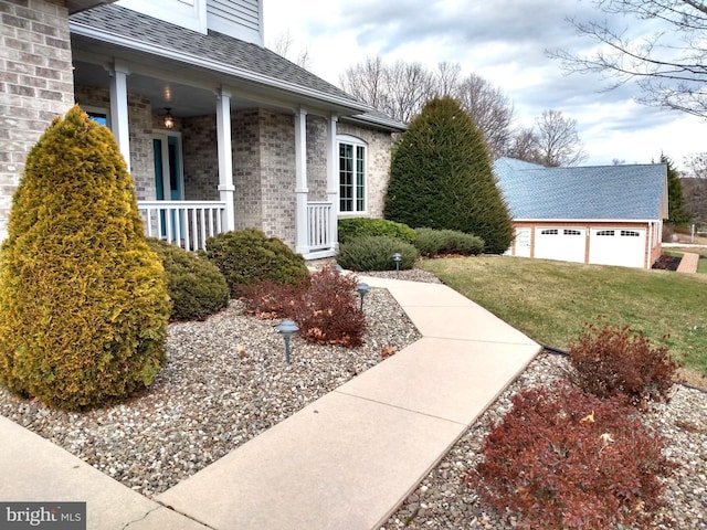 view of front of property with a garage, covered porch, an outdoor structure, and a front lawn