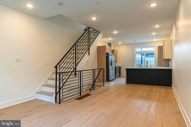 interior space featuring stainless steel fridge with ice dispenser, sink, and light hardwood / wood-style floors