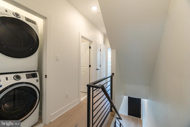 washroom featuring stacked washing maching and dryer and light hardwood / wood-style flooring