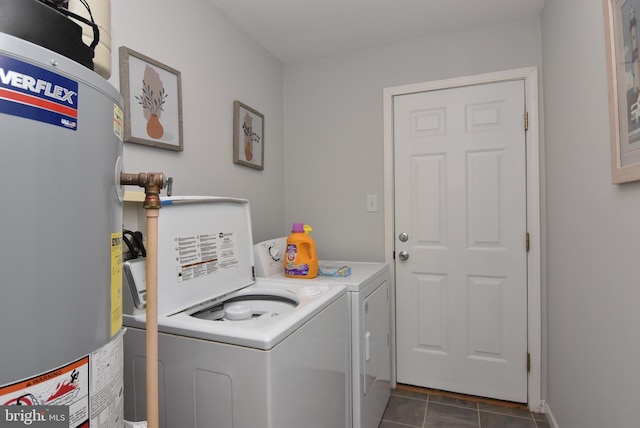 clothes washing area with washer and clothes dryer, dark tile patterned flooring, and water heater