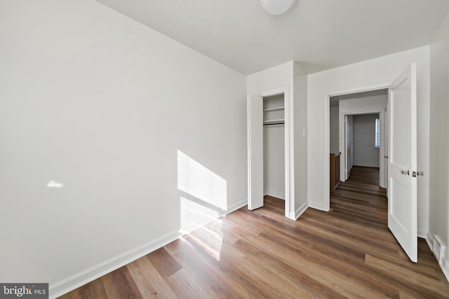 unfurnished bedroom with a closet and dark hardwood / wood-style floors