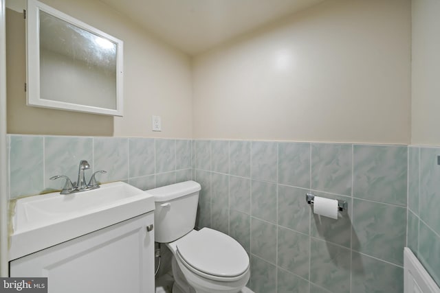 bathroom with vanity, tile walls, and toilet