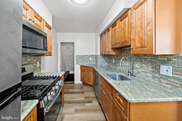 kitchen with light stone counters, sink, appliances with stainless steel finishes, and tasteful backsplash