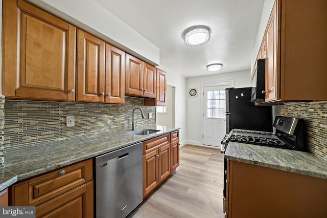 kitchen with backsplash, light stone counters, sink, and appliances with stainless steel finishes