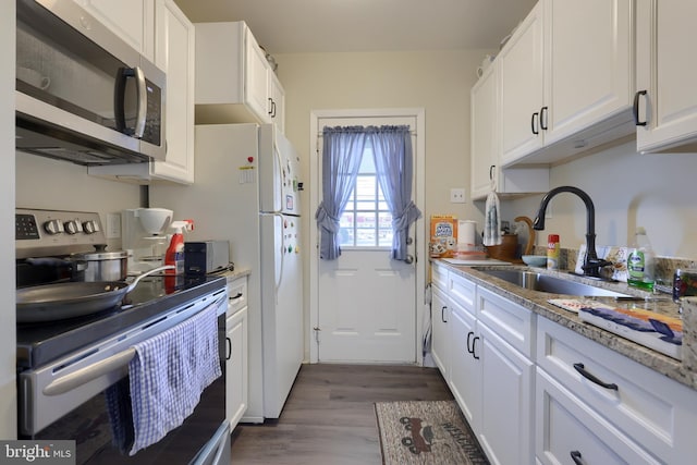 kitchen with light stone countertops, white cabinetry, sink, dark wood-type flooring, and stainless steel appliances