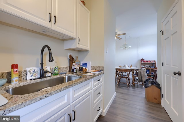 kitchen featuring white cabinetry, sink, and light stone countertops