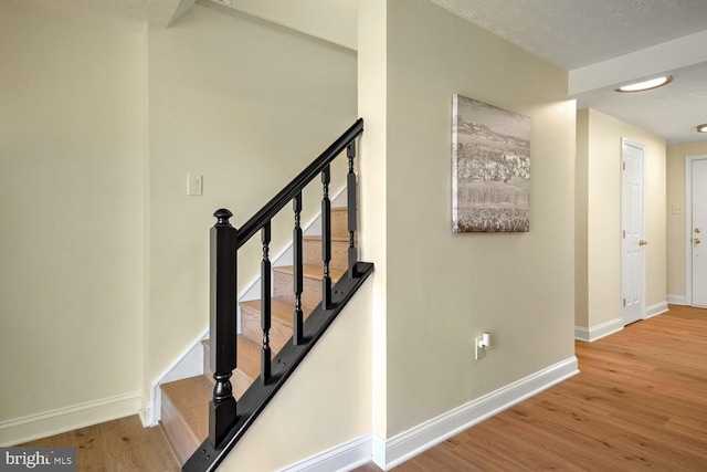 staircase featuring wood-type flooring and a textured ceiling