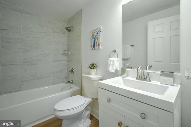 full bathroom featuring wood-type flooring, a textured ceiling, toilet, vanity, and tiled shower / bath