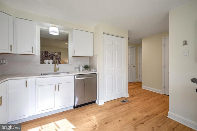 kitchen featuring white cabinets, light hardwood / wood-style floors, stainless steel dishwasher, and sink