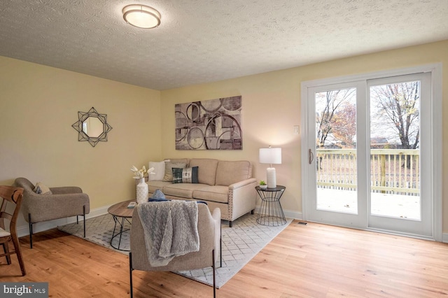 living room with a textured ceiling and light hardwood / wood-style flooring