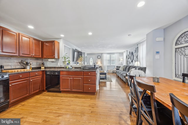 kitchen featuring range, black dishwasher, sink, kitchen peninsula, and light hardwood / wood-style flooring