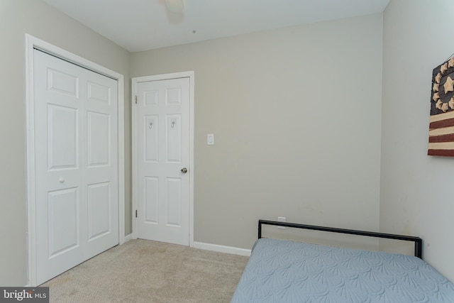 unfurnished bedroom with light carpet, a closet, and ceiling fan