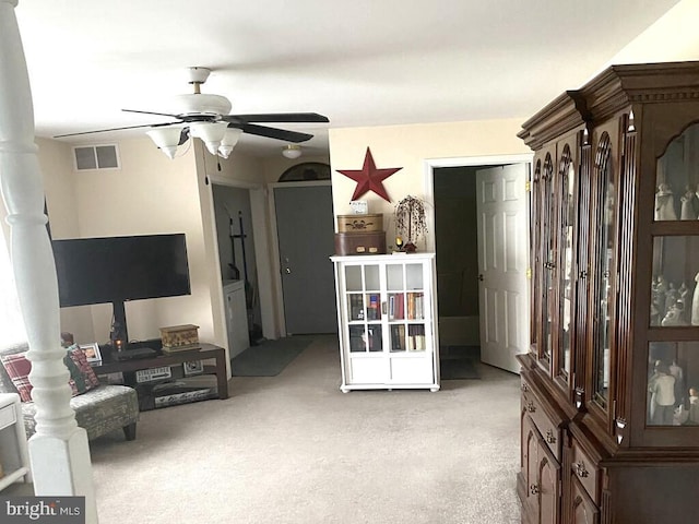 living area with light carpet and ceiling fan