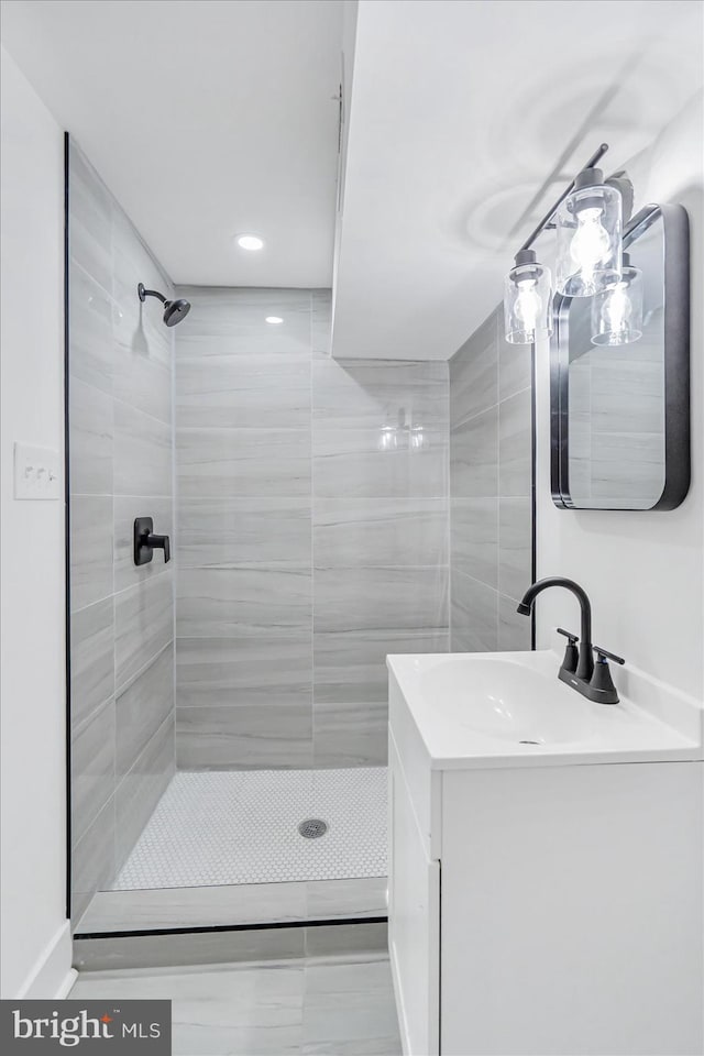 bathroom with tiled shower and vanity