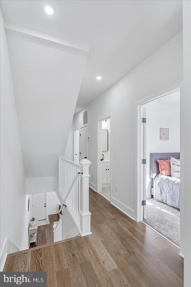 hallway with hardwood / wood-style floors and vaulted ceiling