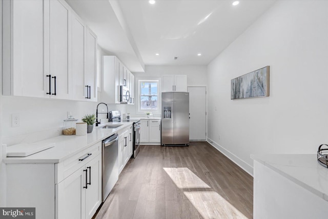 kitchen featuring light stone countertops, white cabinetry, stainless steel appliances, and light wood-type flooring