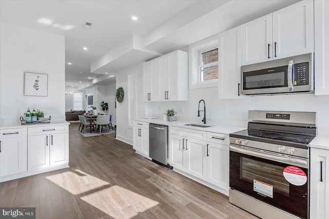 kitchen with light hardwood / wood-style floors, white cabinetry, sink, and appliances with stainless steel finishes