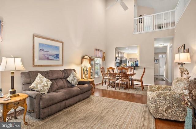 living room with a high ceiling, hardwood / wood-style flooring, and ceiling fan