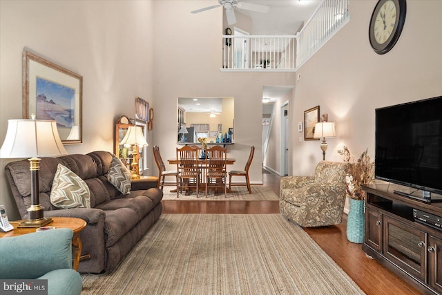 living room featuring ceiling fan, hardwood / wood-style floors, and a high ceiling