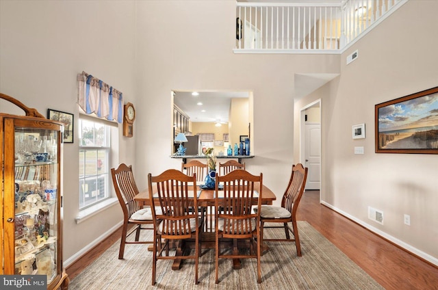 dining space with hardwood / wood-style floors and a towering ceiling