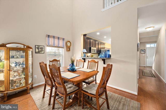 dining space featuring a towering ceiling and dark wood-type flooring