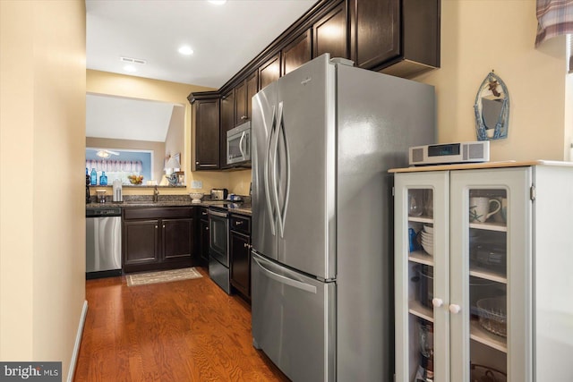 kitchen with sink, stainless steel appliances, dark hardwood / wood-style floors, vaulted ceiling, and dark brown cabinets