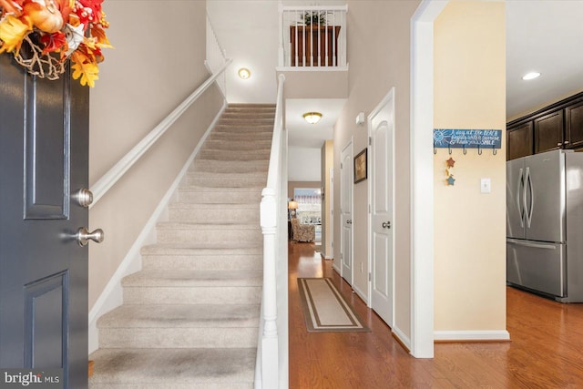 staircase featuring a towering ceiling and wood-type flooring