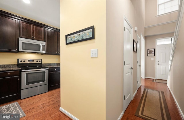 kitchen featuring dark brown cabinetry, appliances with stainless steel finishes, and light hardwood / wood-style flooring