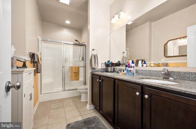 bathroom with toilet, vanity, tile patterned floors, and a shower with door