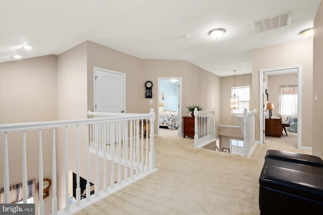 hall featuring light carpet and an inviting chandelier