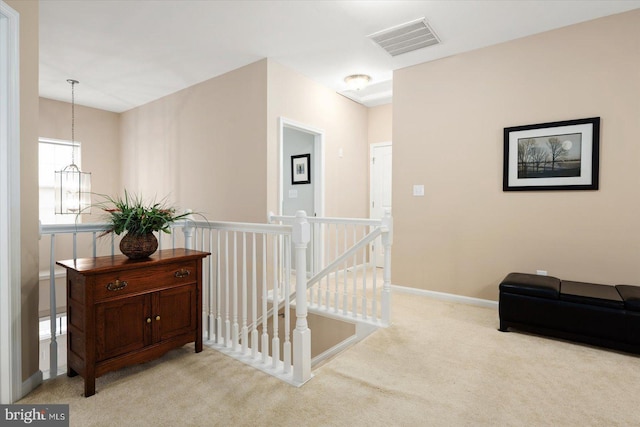 hall with light carpet and an inviting chandelier