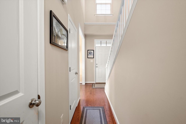 hallway with a towering ceiling and dark wood-type flooring