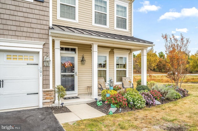 view of exterior entry featuring a porch and a garage