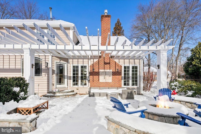 snow covered rear of property featuring a pergola and a fire pit