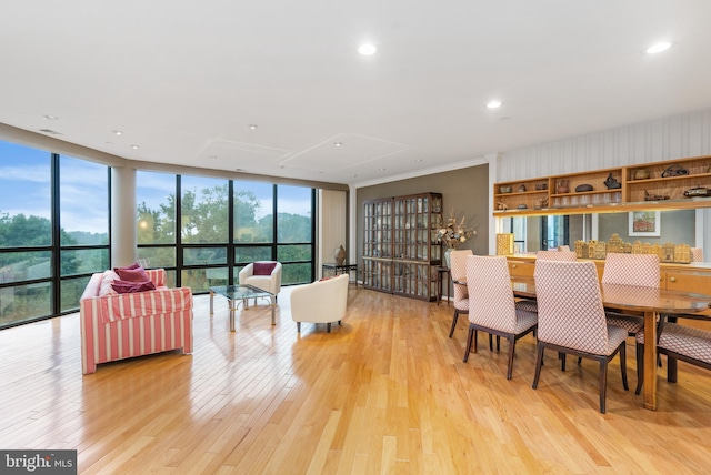 dining space with a wall of windows, crown molding, and light hardwood / wood-style flooring