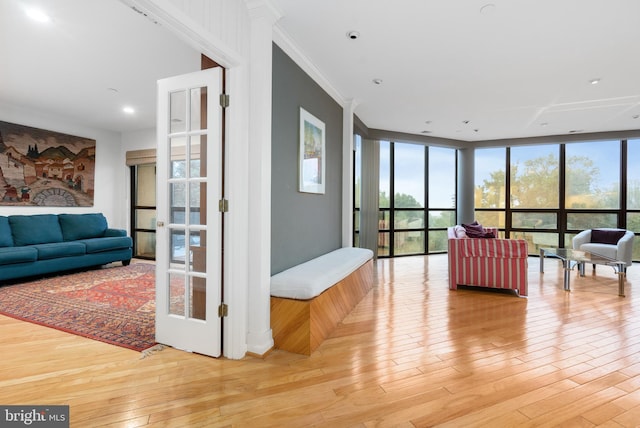 living room with floor to ceiling windows, ornamental molding, and light wood-type flooring